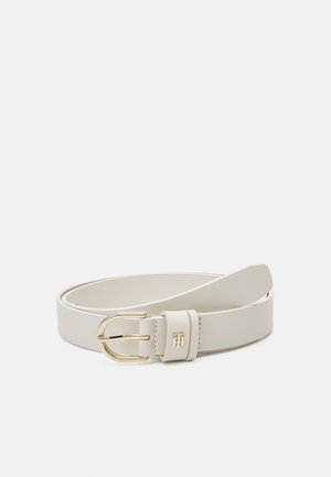 Ceinture en cuir blanc avec boucle en métal doré et petit logo embossé doré sur la boucle de ceinture sur un fond uni.