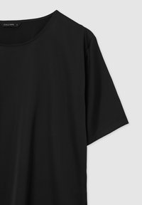 Maglietta nera a maniche corte realizzata in tessuto morbido con scollatura rotonda. Presenta un design semplice, senza motivi o dettagli visibili.