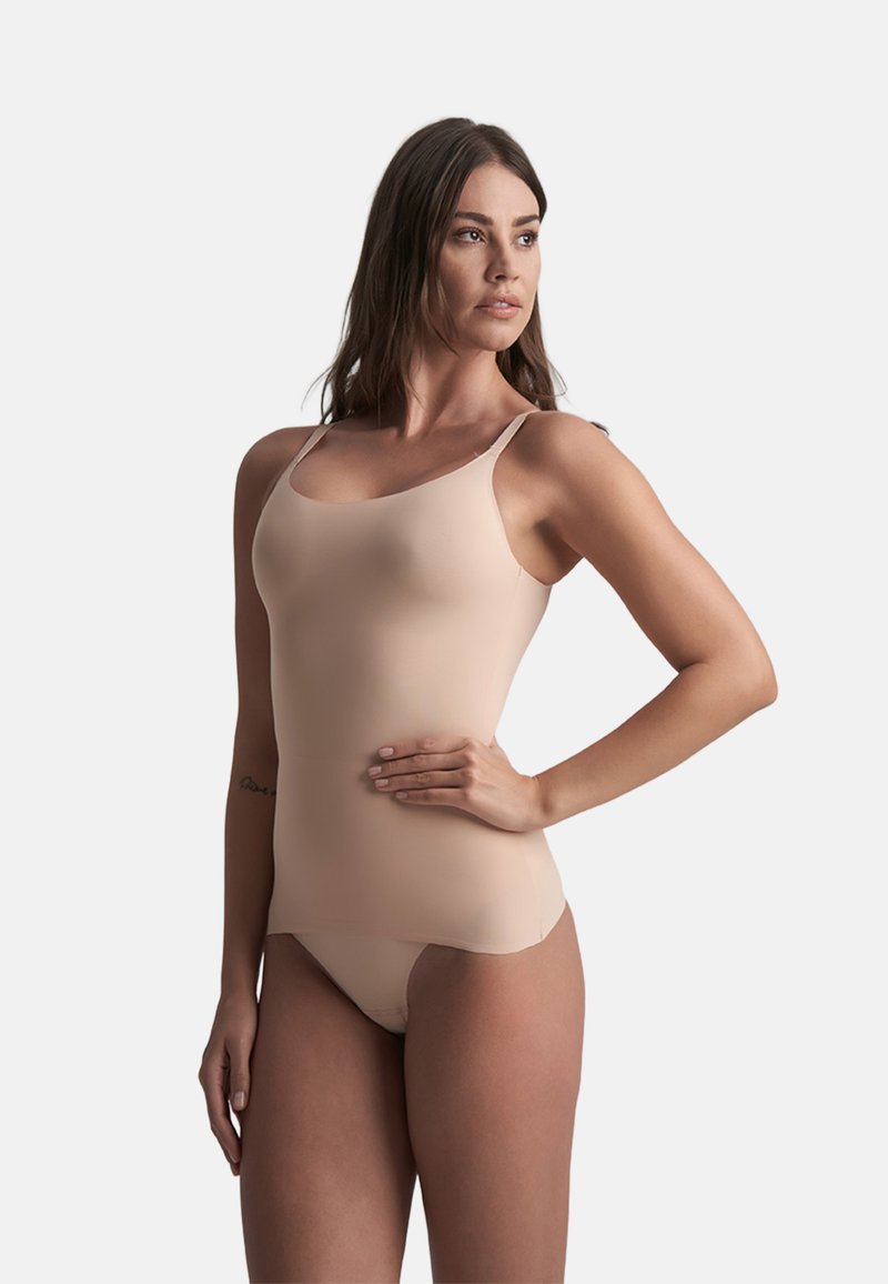 Nerovný tělový těsný tílko s nastavitelnými tenkými ramínky, vyrobené z hladkého, elastického materiálu, s jednoduchým, minimalistickým designem.
