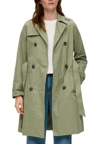 Jasnooliwkowy płaszcz trench z podwójnymi guzikami, kieszeniami bocznymi, szerokim kołnierzem oraz podwiniętymi mankietami, wykonany z gładkiego materiału.