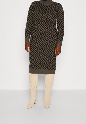Ciemna sukienka dzianinowa z golfem w wzory, noszona z beżowymi kozakami zamszowymi do kolan, pokazana od szyi do stóp na jednolitym tle.