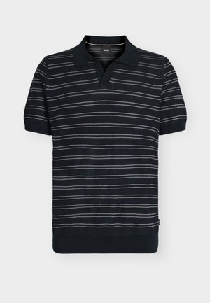 Zwart poloshirt met korte mouwen met witte horizontale zigzagstrepen en geribde zoom en manchetten tegen een effen lichte achtergrond.
