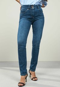 Visoko pasovi modri kavbojki s slim fit krojem, ki imajo dva sprednja žepa, kovinske gumbne zapore in gladko teksturo denim.