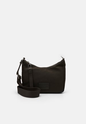 Petit sac bandoulière noir avec sangle réglable, forme rectangulaire, fermeture à glissière et écusson de marque sur le devant, présenté sur un fond blanc uni.