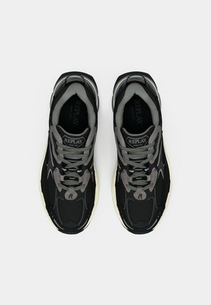 Stel zwarte en grijze Replay merk sportsneakers met lichte zolen, grijze veters en merkzolen, gezien van boven.