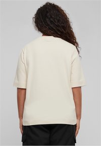 T-shirt kratkih rukava boje krem, izrađen od mekanog materijala, s ravnim krojem i rubom, jednostavnog okruglog dekoltea.