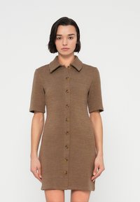 Καφέ πλεκτό φόρεμα με κοντά μανίκια, γιακά και κούμπωμα με κουμπιά μπροστά. Διαθέτει υφή υφάσματος και εφαρμοσ τή σιλουέτα.