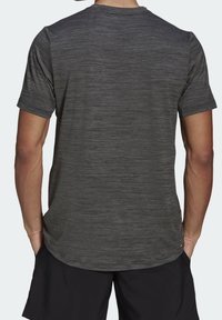 Mörkgrå kortärmad t-shirt i en texturerad, melerad tyg. Har en rund halsringning och en avslappnad passform, lämplig för aktivt bruk.