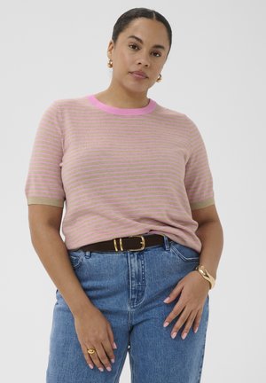 Donna che indossa una maglietta a righe rosa e beige a maniche corte, jeans blu con cintura marrone, orecchini a cerchio dorati, anello e braccialetto.