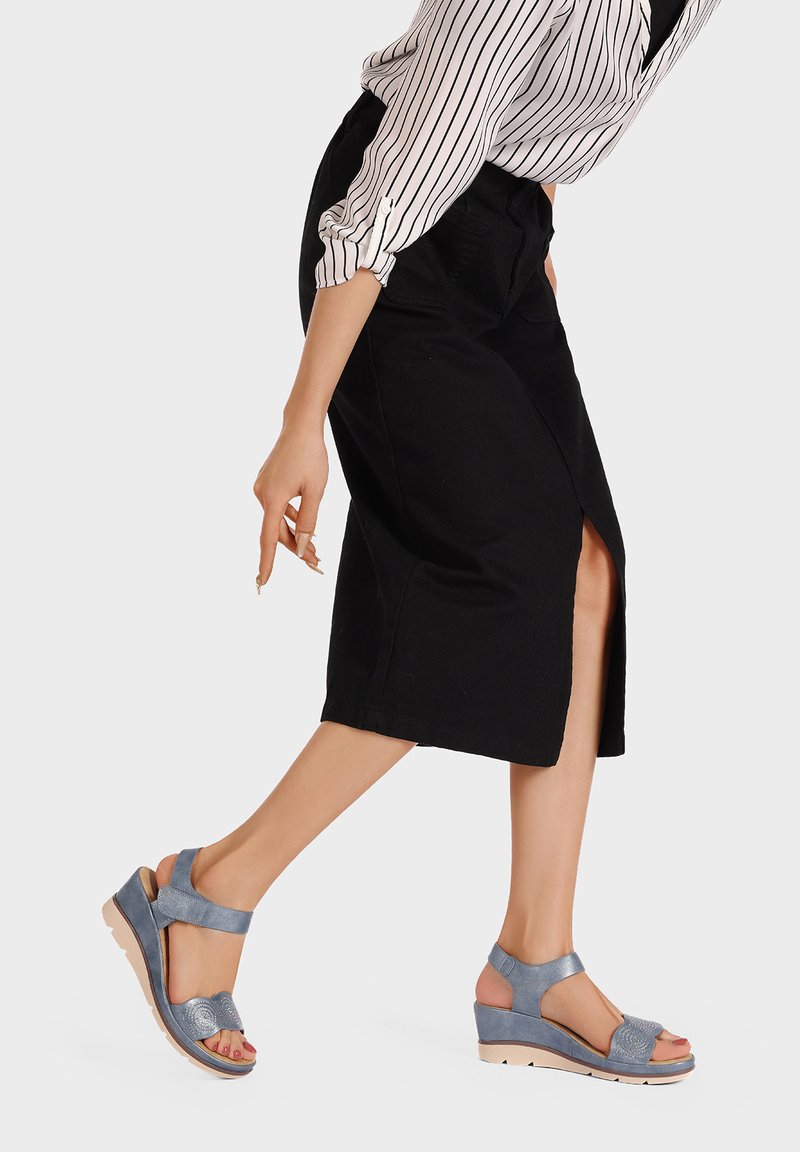 Sandali con zeppa in pelle blu chiaro con cinturini testurizzati e suola imbottita. Il design presenta un cinturino alla caviglia e una punta aperta.