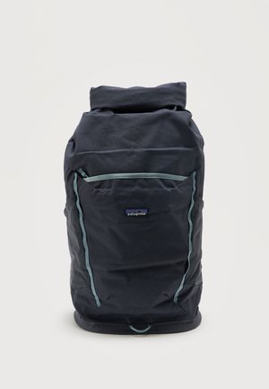 Zaino Patagonia nero con chiusura a rotolo, tasca frontale e rifiniture azzurro chiaro su sfondo bianco uniforme.