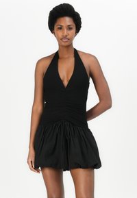 Μαύρο φόρεμα με λαιμόκοψη halter, με εφαρμοστό τοπ και φουσκωτό φουστάνι. Διαθέτει συγκεντρωμένο ύφασμα στο στήθος και ρυθμιζόμενο κορδόνι στη μέση.