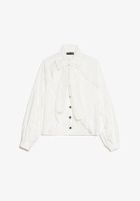 Blusa blanca de manga larga con borde de encaje, cuello con lazo y pequeños botones negros de flores en el frente.