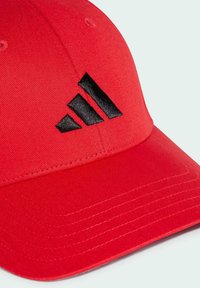 Cappello rosso realizzato in tessuto testurizzato, con un design del logo nero a tre strisce. Visiera curva e dettagli cuciti sono visibili.
