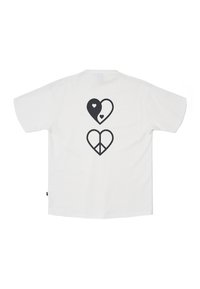 Camiseta blanca de algodón con un gráfico negro en la parte trasera que presenta dos diseños de corazones; uno con un patrón de yin-yang y el otro con un símbolo de paz.