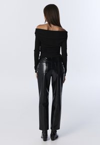 Czarna bluzka typu off-shoulder z długim rękawem, wykonana z teksturowanej tkaniny, zestawiona z wysokim stanem, błyszczącymi spodniami z sztucznej skóry w kolorze czarnym. Prosty, dopasowany fason.