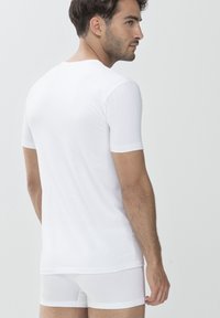 White short-sleeve t-shirt with a round neckline, paired with white fitted shorts. Smooth fabric with a minimalistic design and clean lines.