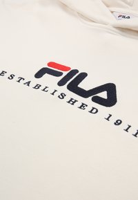 Felpa crema con logo FILA ricamato in nero e rosso sulla parte anteriore, accompagnato dal testo "ESTABLISHED 1911" in nero sotto il logo.