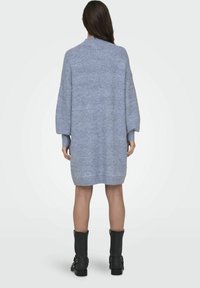 Overdimensjonert blåstrikket kjole med høy hals og lange, lett puffede ermer, med et teksturert strikkemønster og sidesplitter.