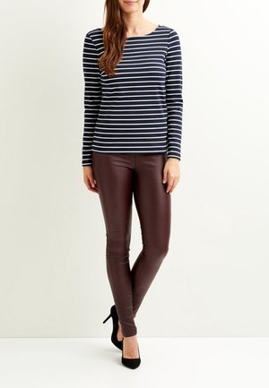 Maglietta a righe blu navy e bianca a maniche lunghe abbinata a leggings in ecopelle marroni e tacchi alti neri. Texture liscia e design aderente.