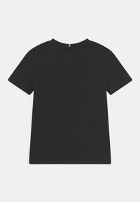 Black cotton t-shirt with short sleeves, crew neck, and a straight hem. Features a small red and white accent on the back neck.