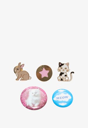 Quatre badges : un lapin beige, une étoile dorée avec un centre rose, un chat noir et blanc, et deux boutons avec un chat blanc sur un fond rose et des nuages bleus portant l'inscription "MEOW."