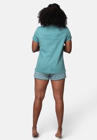 T-shirt turchese con maniche corte, abbinato a pantaloni del pigiama a righe in blu chiaro e bianco. Materiale in cotone morbido, vestibilità casual.