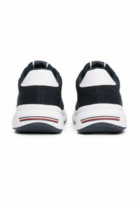 Baskets de sport bleu marine avec une tige en maille respirante, des accents blancs et une semelle blanche texturée avec des rayures rouges et bleues au niveau du talon.