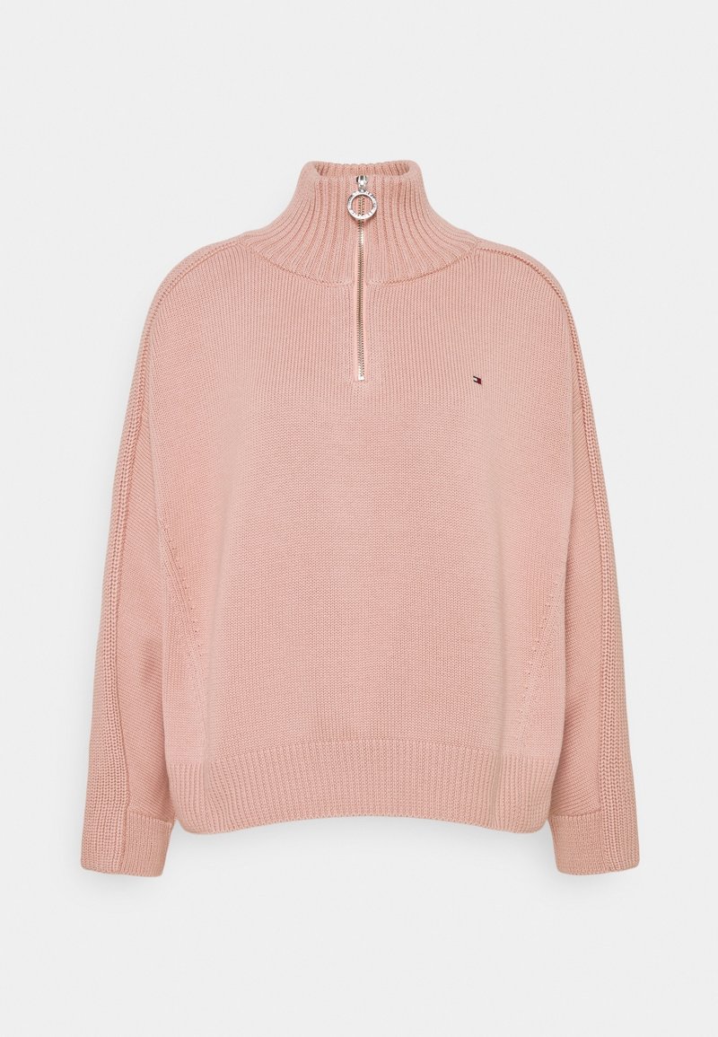 Lichtroze gebreid vest met een hoge hals en een halve rits. Beschikt over brede mouwen en geribbelde manchetten, met een klein logo op de borst.