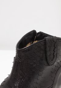 Botas negras hasta el tobillo de cuero texturizado con un patrón escamoso, apertura redondeada y tejido interior en rayas de contraste.