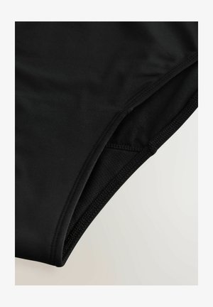 Slipper neri caratterizzati da una superficie liscia, vita elastica e cuciture lungo i bordi.