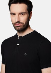 Czarna koszulka polo z krótkim rękawem, z dwoma guzikami na przodzie oraz szarymi akcentami na kołnierzyku i rękawach. Logo wyszyte na piersi.