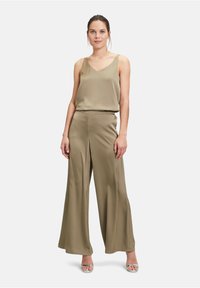 Olijfgroen satijnen camisole top met dunne bandjes, gecombineerd met wijd uitlopende broek in dezelfde kleur, met een soepele textuur en een ontspannen pasvorm.