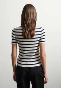 Maglietta a maglia a righe con righe orizzontali blu navy e crema, maniche corte e design aderente. Texture liscia e stile casual.