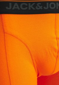Svetlo oranžne moške boksarice s črnim pasom, na katerem je napis "JACK & JONES" v temno sivih črkah.
