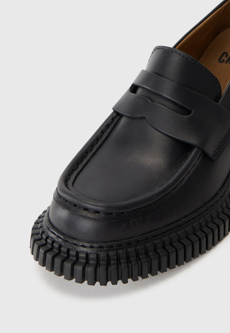 Sort læderloafer med delt stropdesign, tekstureret gummisål, rund tå og kontrastsyninger langs kanten.