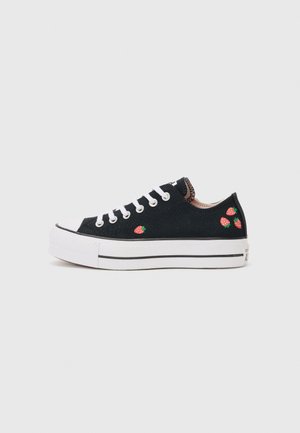 Tenis de tela pretos com sola de borracha branca, apresentando três designs de morangos bordados. Parte frontal com atacadores e detalhes em preto e branco.