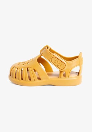 Sandelă din plastic galben, cu un design deschis, având curele flexibile, o cataramă sigură și o talpă texturată pentru confort.