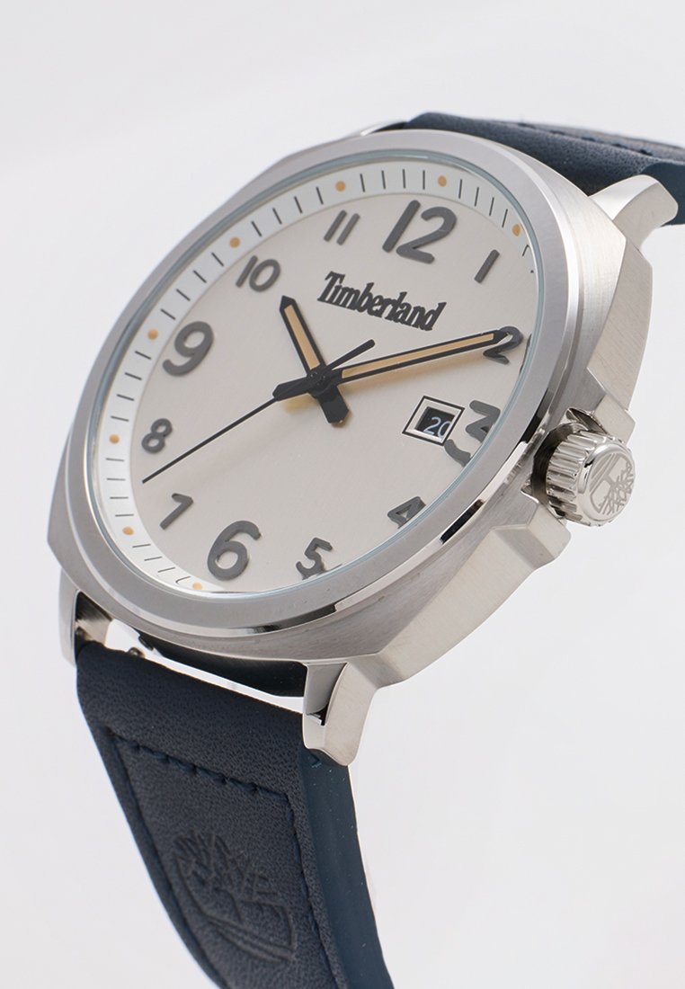 Orologio in acciaio inox argentato con quadrante rotondo, dial bianco, numeri arabi neri e cinturino in pelle blu. Indicatore della data alle 3.