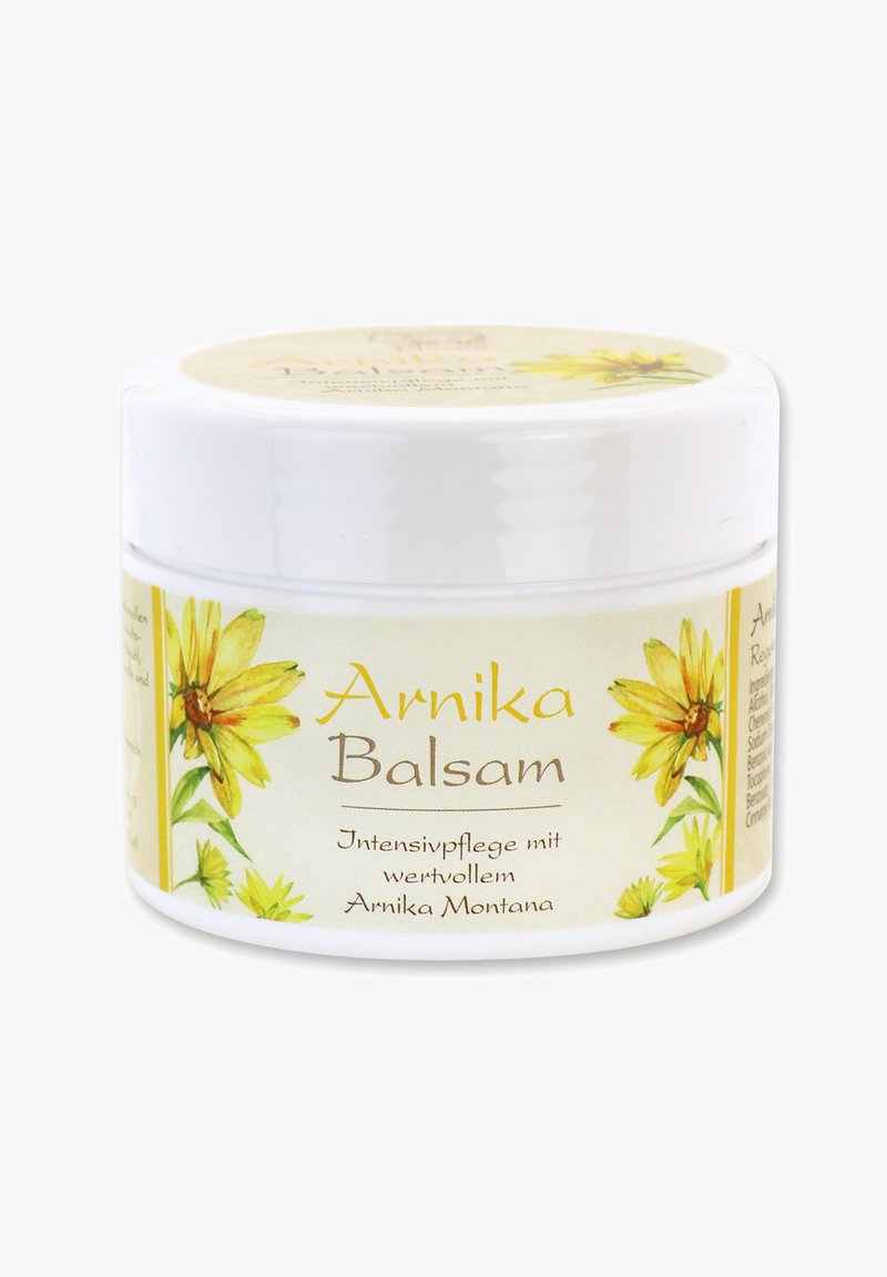 Weißes Plastikgefäß mit einem gelb-grünen Blumendesign als Etikett. Der Text enthält "Arnika Balsam" in brauner Schrift, mit weiteren Produktdetails darunter.