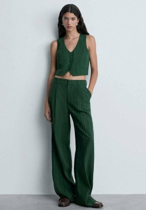 Grøn stribet cropped vest med to knapper og matchende brede bukser lavet af blødt stof. Skoene er brune med slip-on design.