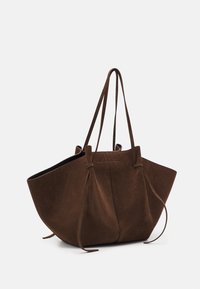 Brązowa torba tote z zamszu o miękkiej teksturze, z otwartym topem i sznurkiem do zamykania. Posiada dwa długie, cienkie uchwyty do noszenia.