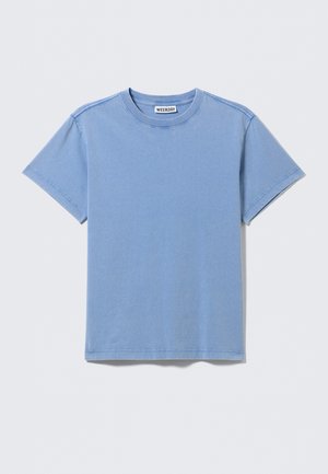 Μονόχρωμο ανοιχτό μπλε βαμβακερό κοντομάνικο T-shirt με στρογγυλή λαιμόκοψη, εμφανείς ραφές και μικρή λευκή ετικέτα μάρκας μέσα στον γιακά.