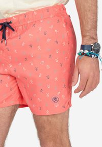 Bañador de coral con cintura elástica, cordón y diseño estampado que presenta pequeños iconos en azul y blanco. Incluye un parche con el logo.