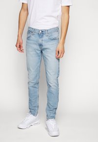 Ljust blå denimjeans med slim fit, som har en klassisk femficka design, subtila stygn och en dragkedja med knäppning.