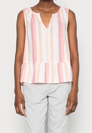 Bluzka bez rękawów z pionowymi różowymi, brzoskwiniowymi i białymi paskami, z małym dekoltem w serek i falbanką na dole, noszona z jasnoszarymi spodniami.