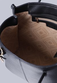 Indvendig af en sort lædertaske med tekstureret overflade, der har en lynlås lomme og en beige foring med gentagne brandlogo mønstre.