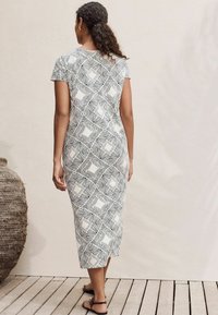 Maxikleid in Schwarz und Weiß mit geometrischem Muster. Kurze Ärmel, taillierte Silhouette, weicher Stoff und knielanger Saum.