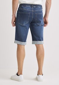 Tummansiniset rentot, farkkushortsit, joissa käännetty lahje ja joustava vyötärönauha. Varustettu kahdella takataskulla ja hillityllä ompeludetaljilla.