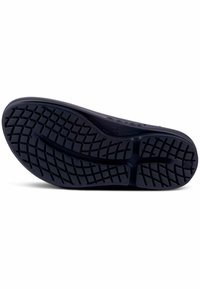 Black rubber shoe sole with a textured, patterned surface for grip, featuring a central groove and rounded edges for flexibility.